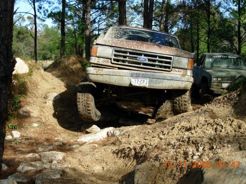 1987 Ford Bronco - 1987 Ford Bronco tackling a challenging off-road course with another vehicle in the background.