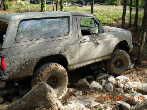 1987 Ford Bronco - This SUV is navigating a rocky obstacle course, covered in mud from the trail.