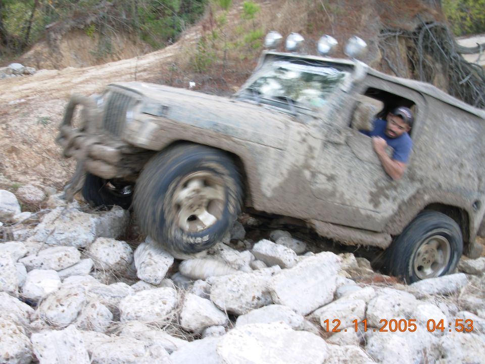 Muddy off-road vehicle navigating rocky terrain