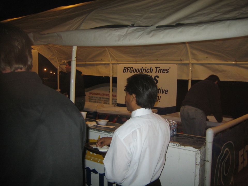 People at a nighttime outdoor BFGoodrich Tires booth under a white canopy