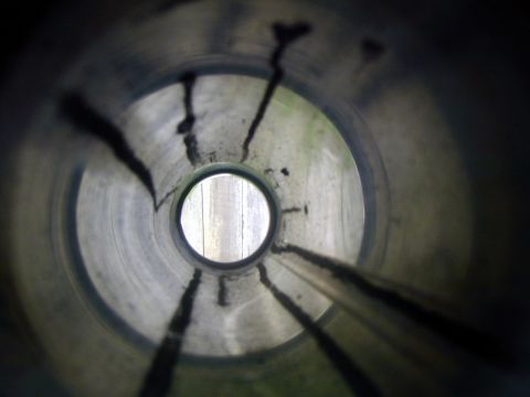2000 Ford Crown Victoria - View from inside an exhaust pipe shows carbon deposits and a circular opening revealing wooden planks.