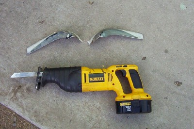 1995 Ford Bronco - A DeWalt reciprocating saw and two chrome trim pieces are laid out on a concrete surface.