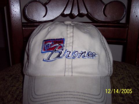 1979 Ford Bronco - A white baseball cap features embroidered text that reads 'Bronco' in blue script with a red and blue rectangular logo above it.