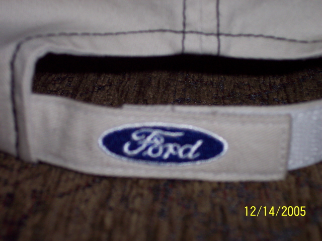 Close-up of a tan cap with a blue Ford logo on the band. Date 12/14/2005 and Supermotors.net visible