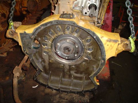 1966 International School Bus - Close-up view of a heavy-duty yellow engine component, likely a transmission housing, suspended by chains.