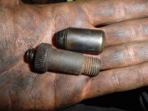 1966 International School Bus - Close-up of an engine bolt and cap held in a greasy hand.