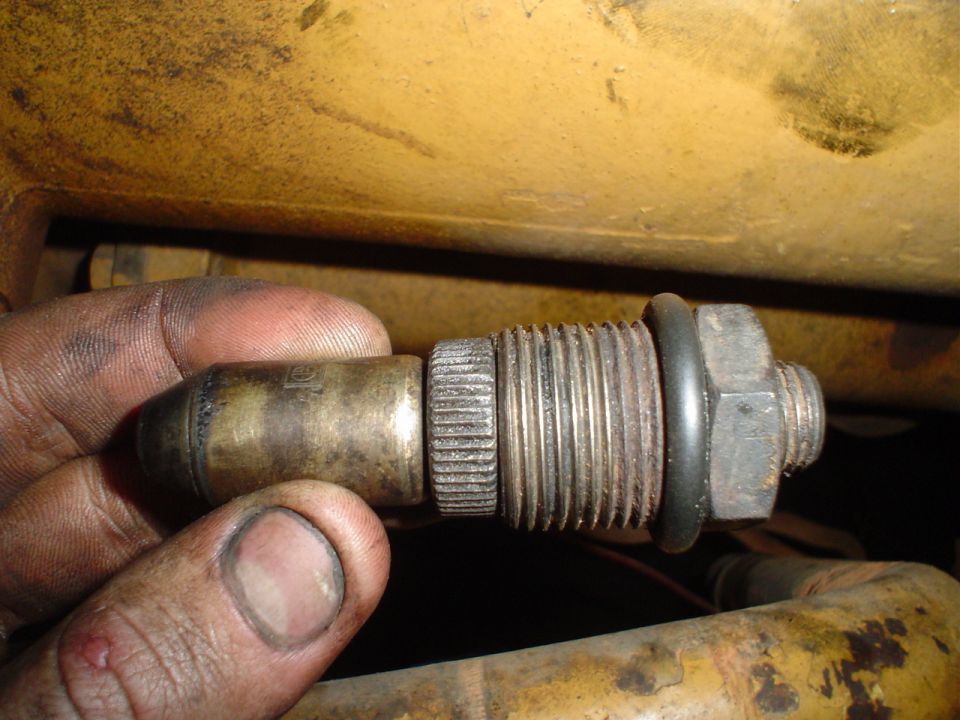 Hand holding brass engine sensor with threaded end and rubber o-ring