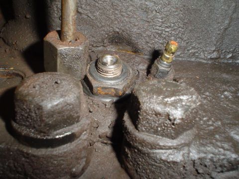 1966 International School Bus - Detail shot of engine parts, including various nuts and a small brass valve, covered in grime.