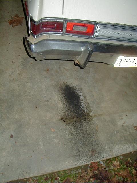 1993 Ford Bronco - A dark fluid stain is visible on the concrete beneath the rear bumper of a vehicle.