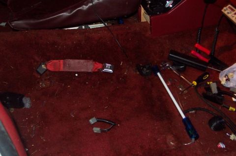 1985 Ford LTD Crown Victoria - Interior view of a vehicle showing a red seatbelt and carpeting, with tools scattered on the floor.