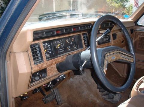 1986 Ford Bronco - The dashboard of a 1986 Ford Bronco shows gauges, vents, and a steering wheel with wood-grain accents.