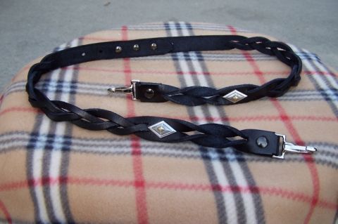 1990 Ford Bronco - Two braided leather straps with decorative diamond accents and metal clasps are displayed on a plaid fabric surface.