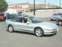 1994 Ford Probe - A silver coupe is parked in a lot with other vehicles visible.