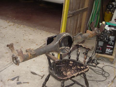 1989 Ford Bronco - Rear axle assembly, likely from a truck or SUV, sits on a chair with a welder nearby.