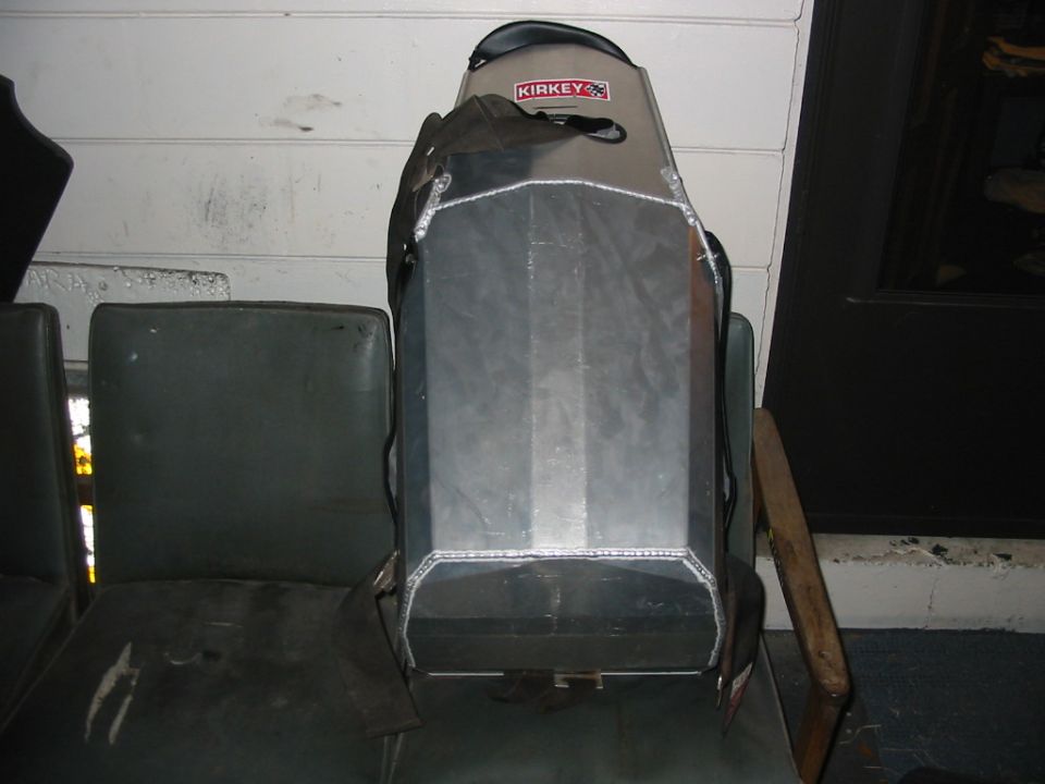 Metal object with "KIRKEY" logo on a dark seat, next to another seat