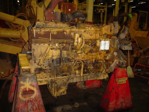 1966 International School Bus - A large, yellow engine is supported by red jack stands in what appears to be a workshop.
