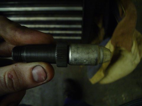 1966 International School Bus - Close-up of a metal component, likely an engine part, being held for inspection.