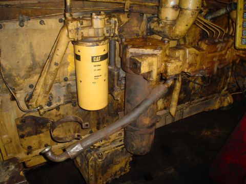 1966 International School Bus - A close-up view of engine components, including a CAT oil filter and various pipes.