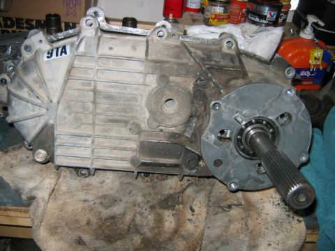 1992 Ford Bronco - A cast-aluminum transfer case sits on a padded workbench, its front output flange with splined output shaft and bearing visible on the righ…