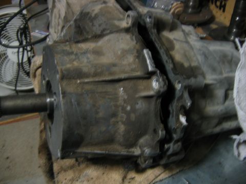 1992 Ford Bronco - A dirty, oil-stained manual transmission or transfer case housing sits on a cloth-covered surface in a workshop, with the input/output shaf…