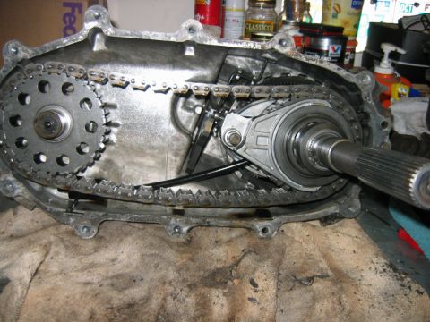 1992 Ford Bronco - Opened transfer case on a workbench revealing the internal drive chain, sprockets and splined output shaft.