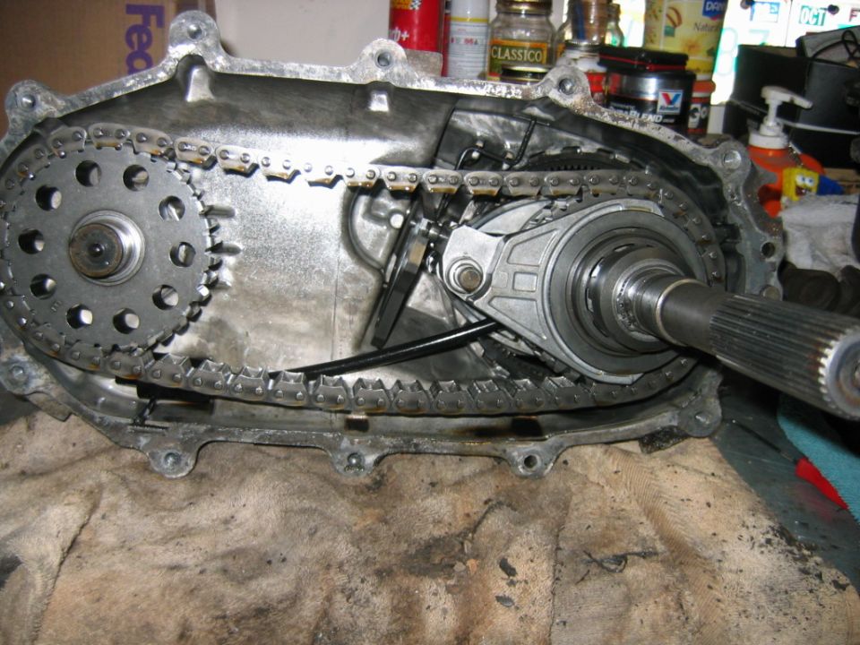 Open transfer case showing drive chain, sprockets and output shaft on a workbench