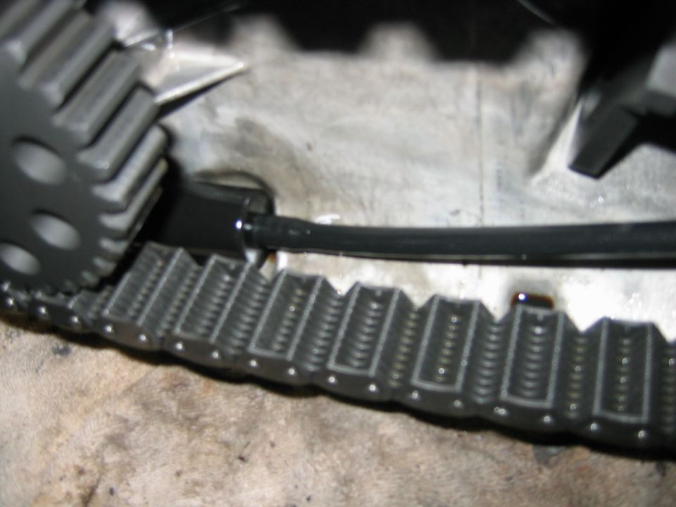 Gray toothed gear engaging a segmented track with black cables above