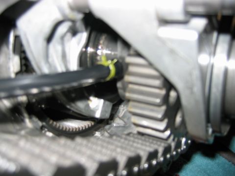 1992 Ford Bronco - Macro shot inside an engine bay showing timing chain gears, a cam sprocket with a yellow marker, and surrounding aluminum castings.