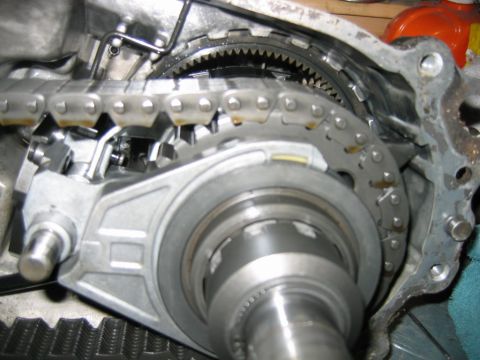 1992 Ford Bronco - Close-up of an opened transfer case interior showing a heavy-duty drive chain wrapping around sprockets, a toothed ring gear, and a splined…