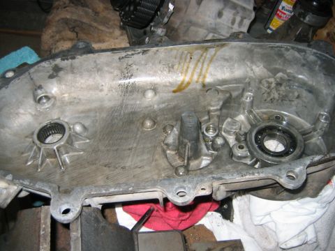 1992 Ford Bronco - Interior of an aluminum transmission/transfer case cover casting laid open on a workbench, showing a splined output hub, a ball bearing, ma…