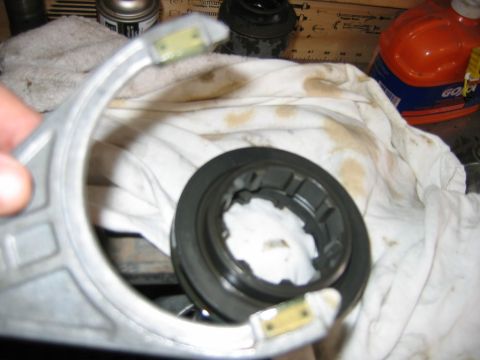 1992 Ford Bronco - Close-up of an automotive part being held over a shop rag, showing an aluminum bracket or steering knuckle with a dark plastic ring or bear…