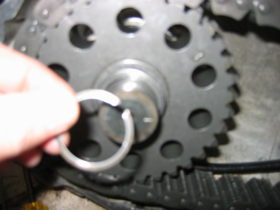 Hand holding a snap ring near a timing gear on a splined shaft