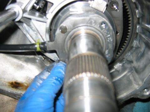 1992 Ford Bronco - Close-up of a splined transmission output/input shaft protruding from an aluminum transmission bellhousing, with a visible ring gear and a…