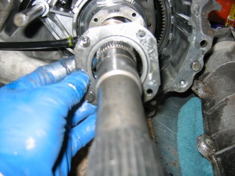 1992 Ford Bronco - Close-up of a transmission or transfer case output shaft with splined tip, held near an aluminum housing bearing bore. A blue-gloved hand s…