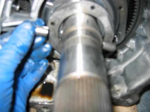 1992 Ford Bronco - Slightly out-of-focus close-up of drivetrain work: a polished, splined output shaft protruding from an aluminum transmission or transfer-ca…