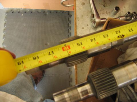 1992 Ford Bronco - A splined transmission or transfer case output shaft being measured with a yellow tape measure reading about 16-17 inches. The steel shaft…