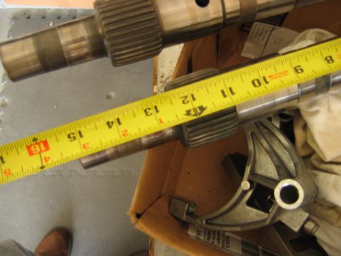 1992 Ford Bronco - Two splined transmission shafts laid across an open cardboard box, with a yellow tape measure showing roughly 8 to 16 inches stretched alon…