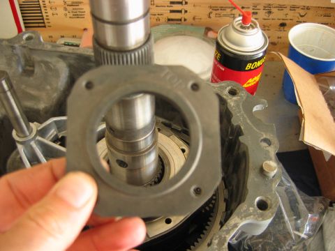 1992 Ford Bronco - A hand holds a black gasket molded with the word TOP over the splined output shaft of a partially disassembled transmission/transfer case o…