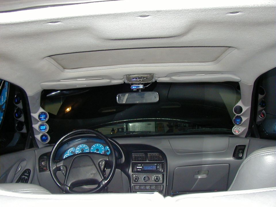 Car interior from rear seat with blue-lit gauges, A-pillar gauge pods and gray dash