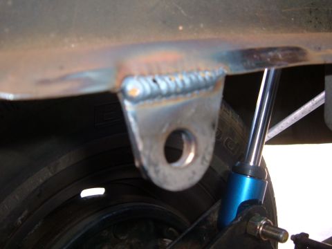 1985 Ford Ranger - Close-up view of a welded bracket on a vehicle's frame, adjacent to a tire and a blue shock absorber.
