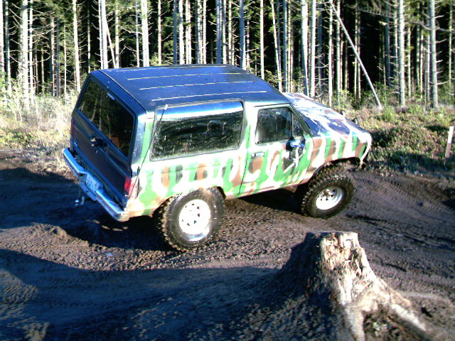 1987 Ford Bronco II with camouflage paint, lifted suspension, and off-road tires on a dirt track