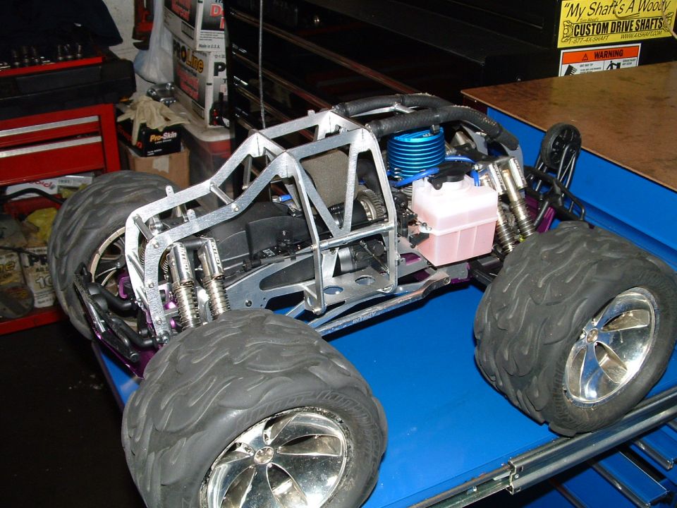 Remote control monster truck with a metal frame, large tires, and a blue engine