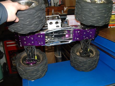1994 Ford Bronco - Close-up view of a remote control monster truck chassis with large, patterned tires and purple accents.