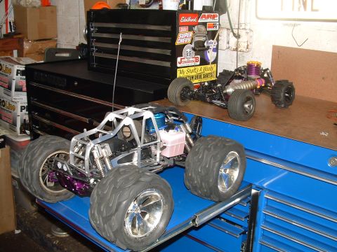 1994 Ford Bronco - Two remote control monster trucks are displayed on a workbench next to a toolbox.