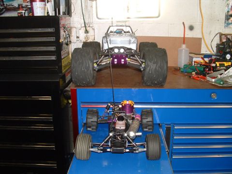 1994 Ford Bronco - Two RC monster trucks are displayed on a blue toolbox in a workshop setting.