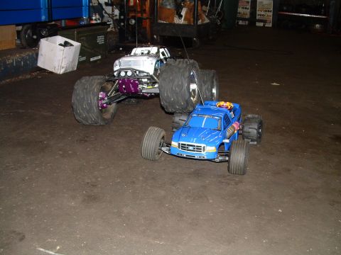 1994 Ford Bronco - Two remote control trucks, one blue and one white, are parked on a concrete floor.