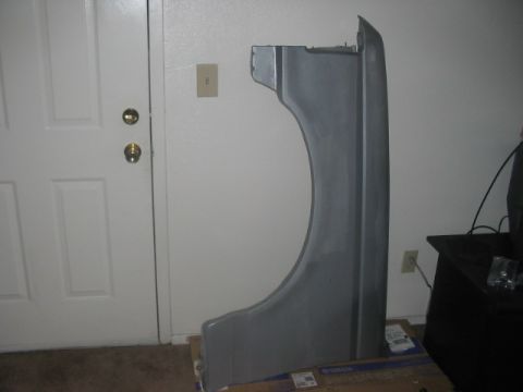 1991 Ford Bronco - A gray car fender is shown indoors, leaning against a wall next to a white door.