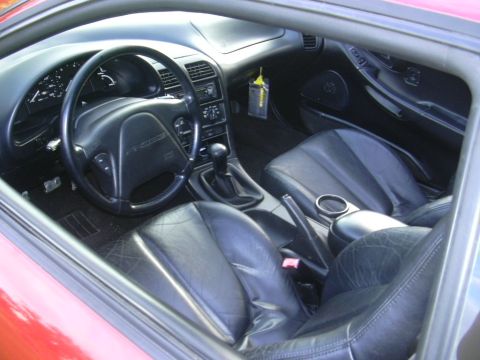 1997 Ford Probe - Interior view of a red 1997 Ford Probe, showing the driver's side dashboard, seats, and center console.