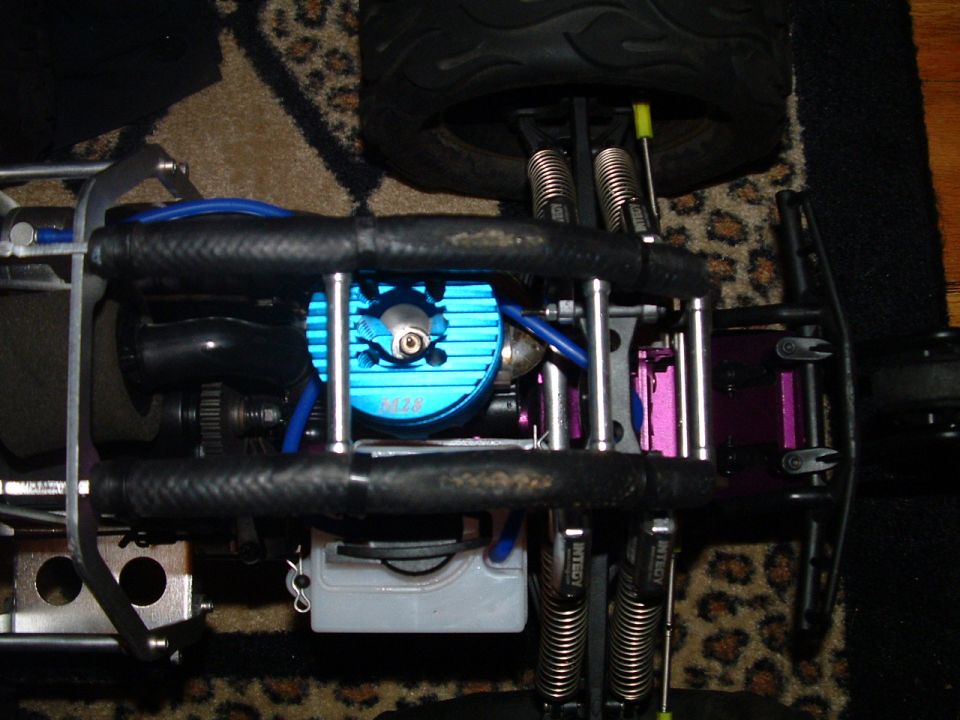 close-up of blue engine on a remote control car, with suspension and fuel tank visible