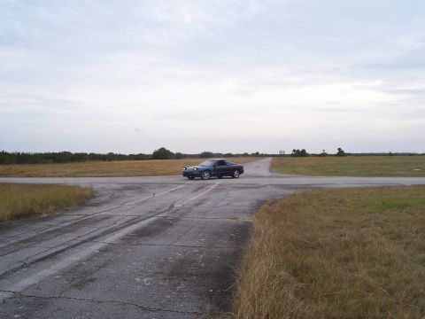 1994 Ford Probe - A dark blue 1994 Ford Probe is seen driving on a paved road in an open field.
